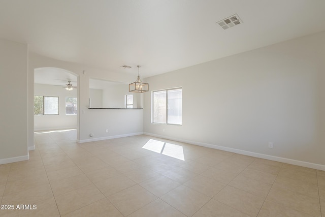 unfurnished room featuring arched walkways, visible vents, and a healthy amount of sunlight