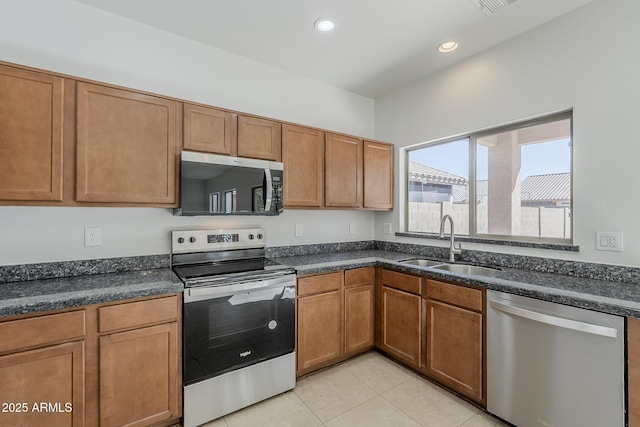 kitchen featuring light tile patterned flooring, recessed lighting, a sink, appliances with stainless steel finishes, and brown cabinets