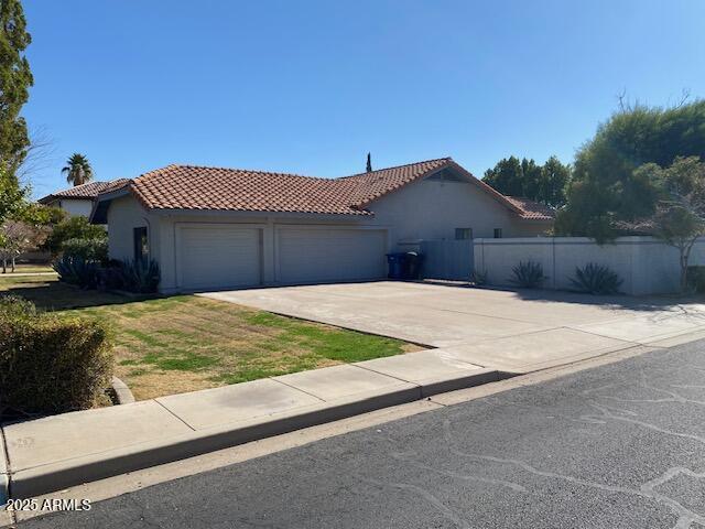 mediterranean / spanish home with stucco siding, concrete driveway, an attached garage, and a tiled roof