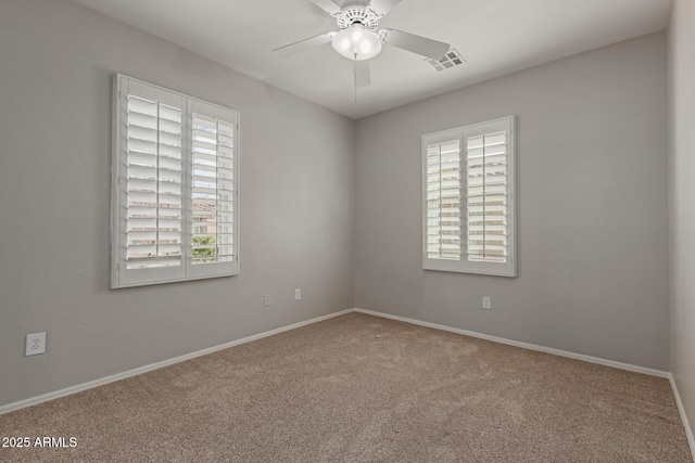 empty room featuring carpet, a ceiling fan, visible vents, and baseboards