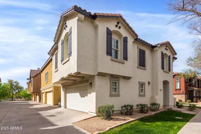 view of front of property featuring stucco siding, driveway, an attached garage, and a tile roof