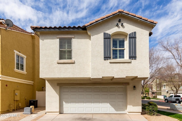 view of front of property with stucco siding, concrete driveway, an attached garage, and a tiled roof