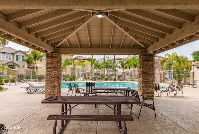 view of patio with a gazebo, a community pool, and fence