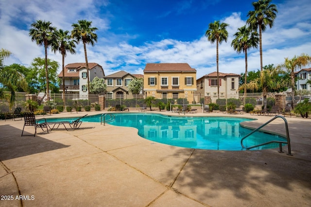 community pool with a patio area, a residential view, and fence