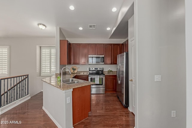 kitchen with visible vents, dark wood-type flooring, a sink, appliances with stainless steel finishes, and a peninsula