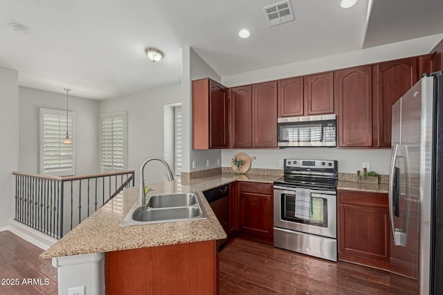 kitchen featuring dark wood finished floors, a peninsula, appliances with stainless steel finishes, and a sink