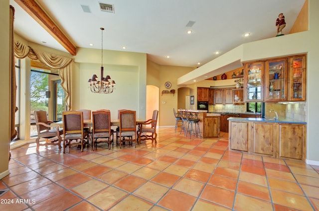 dining room with beam ceiling, sink, light tile patterned floors, a chandelier, and a towering ceiling