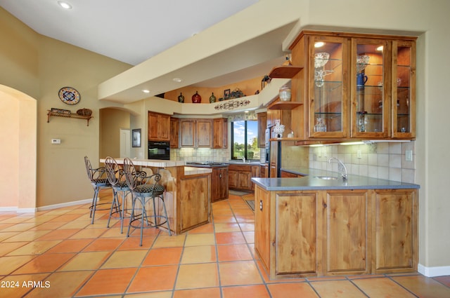 kitchen featuring kitchen peninsula, a kitchen bar, light tile patterned floors, and oven