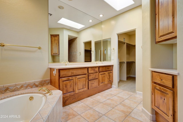 bathroom with vanity, a relaxing tiled tub, a skylight, and tile patterned flooring