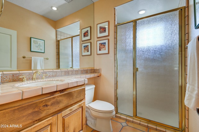 bathroom with a shower with door, vanity, toilet, and tile patterned flooring