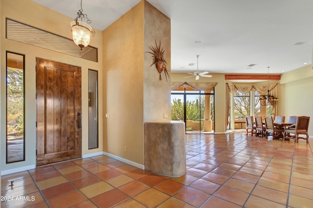 entryway featuring tile patterned flooring and ceiling fan with notable chandelier