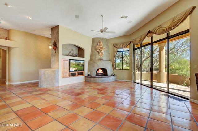 unfurnished living room with ceiling fan, a fireplace, and light tile patterned floors