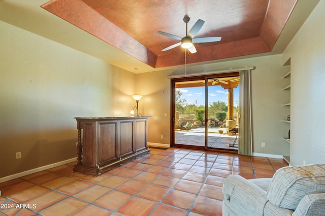 living area featuring ceiling fan, a raised ceiling, built in features, and light tile patterned floors