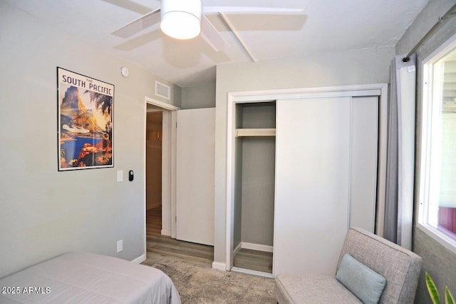 bedroom featuring visible vents, a closet, wood finished floors, baseboards, and ceiling fan