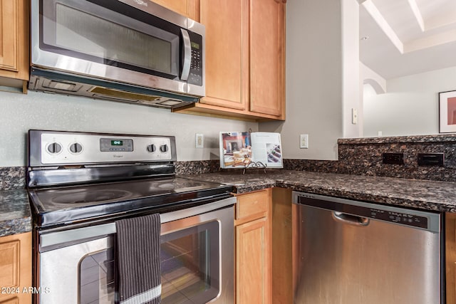 kitchen with appliances with stainless steel finishes and dark stone countertops