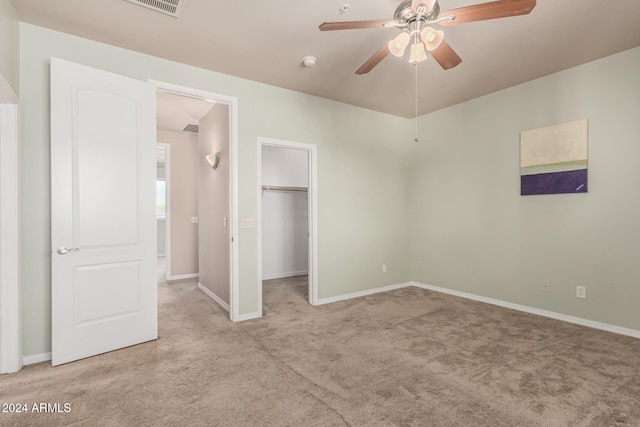 unfurnished bedroom with ceiling fan, light colored carpet, a spacious closet, and a closet