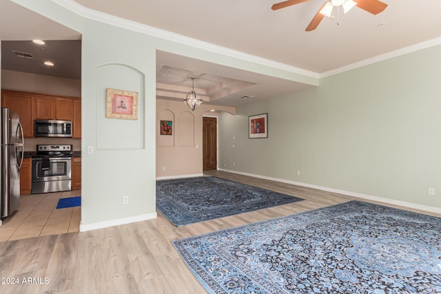 interior space with ceiling fan, light hardwood / wood-style floors, a raised ceiling, and ornamental molding