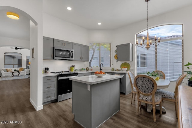 kitchen featuring appliances with stainless steel finishes, dark hardwood / wood-style flooring, gray cabinetry, pendant lighting, and a kitchen island