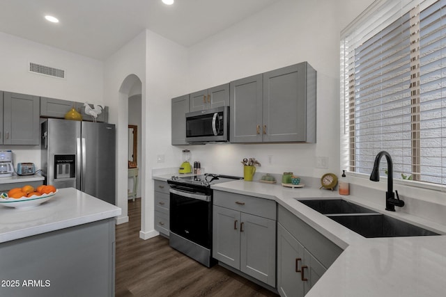 kitchen with gray cabinets, sink, stainless steel appliances, and dark hardwood / wood-style floors