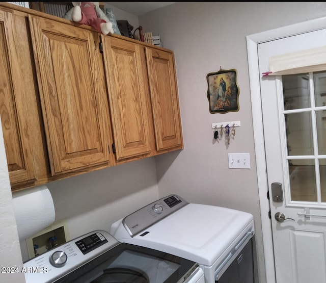 clothes washing area with washing machine and dryer and cabinets