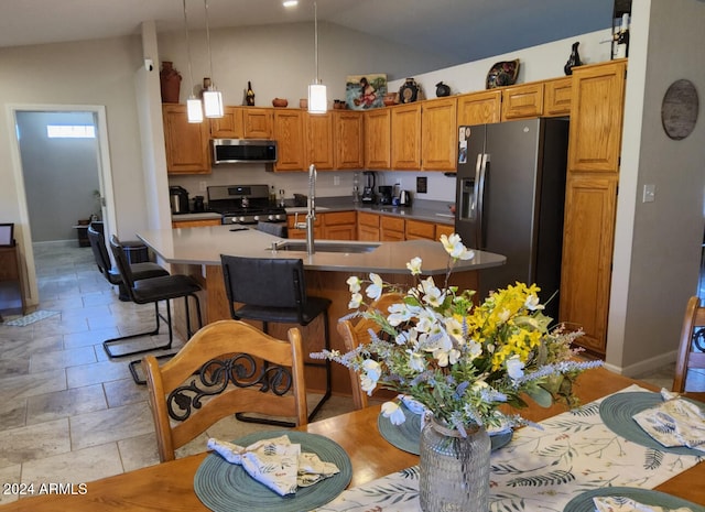 kitchen with appliances with stainless steel finishes, hanging light fixtures, sink, a breakfast bar area, and lofted ceiling