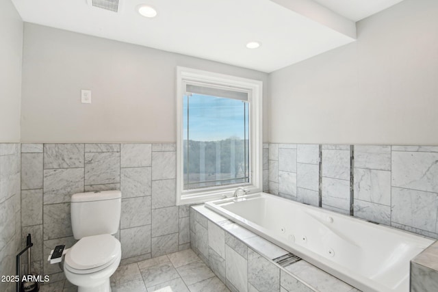 bathroom featuring tiled bath, tile walls, and toilet