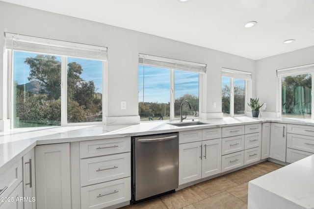 kitchen featuring dishwasher, sink, light stone countertops, and white cabinets