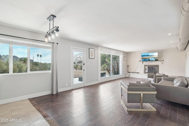 living room with a brick fireplace, plenty of natural light, and dark hardwood / wood-style floors