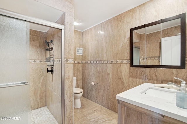 bathroom with a shower with door, vanity, tile walls, and toilet