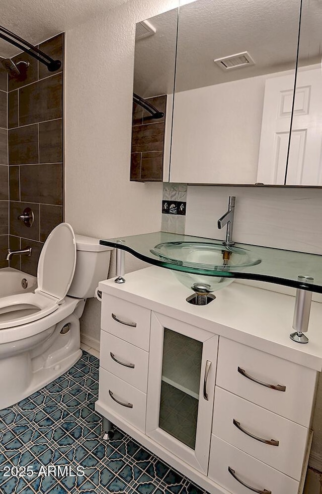 full bathroom featuring vanity, toilet, a textured ceiling, and tiled shower / bath