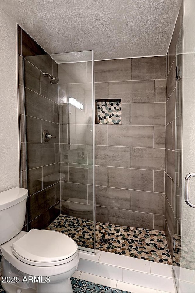 bathroom featuring an enclosed shower, a textured ceiling, and toilet