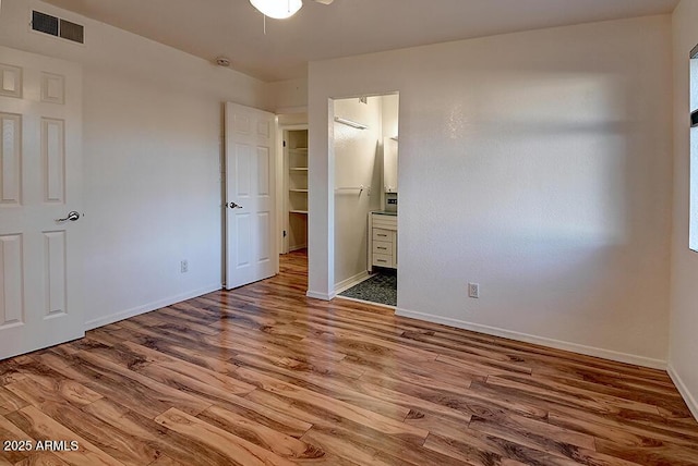 unfurnished bedroom featuring ensuite bath and hardwood / wood-style floors