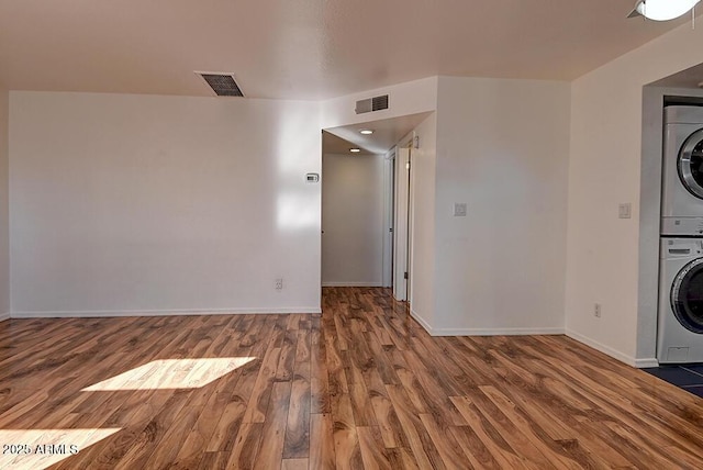 laundry room featuring stacked washer and dryer and hardwood / wood-style floors