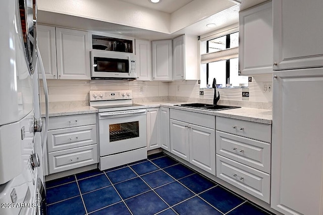 kitchen featuring sink, backsplash, white cabinets, and white appliances