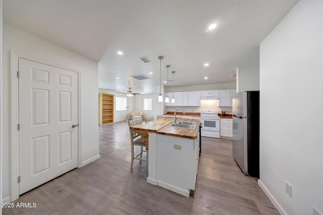 kitchen with wood finished floors, white electric stove, freestanding refrigerator, a sink, and wood counters