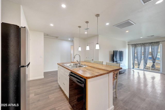 kitchen with visible vents, a sink, freestanding refrigerator, wooden counters, and dishwasher