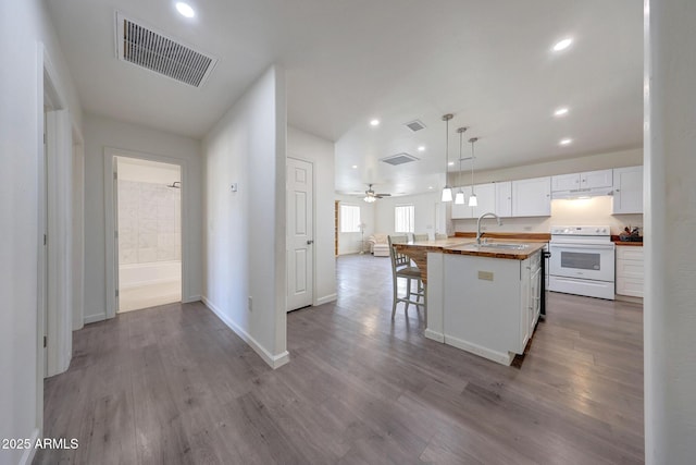 kitchen featuring visible vents, wooden counters, open floor plan, white electric range oven, and a sink