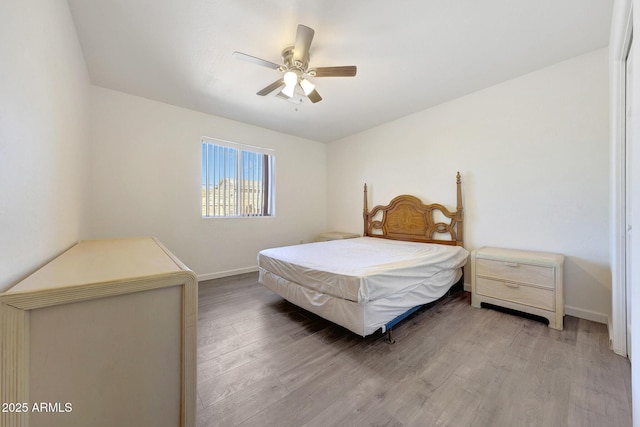 bedroom with light wood-style flooring, a ceiling fan, and baseboards