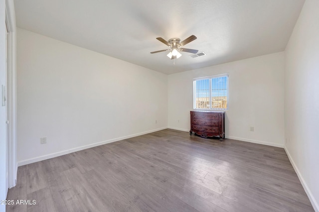 unfurnished room with visible vents, baseboards, wood finished floors, and a ceiling fan