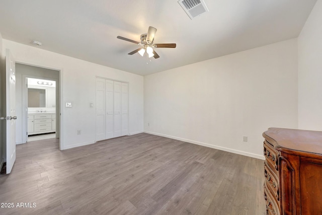 unfurnished bedroom featuring visible vents, a ceiling fan, wood finished floors, a closet, and baseboards