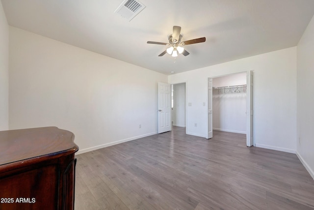 unfurnished bedroom featuring visible vents, a ceiling fan, baseboards, and wood finished floors