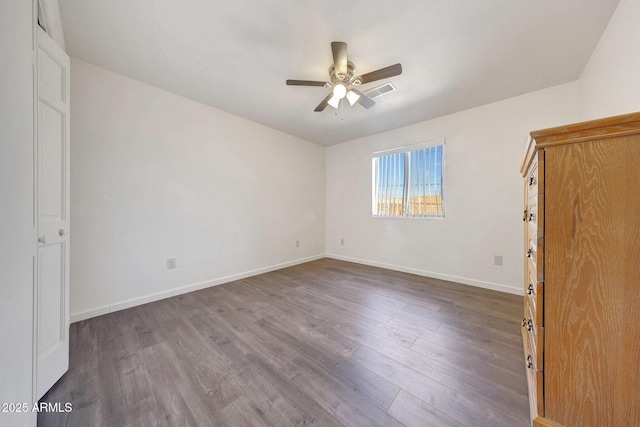 unfurnished bedroom with a ceiling fan, dark wood-type flooring, and baseboards