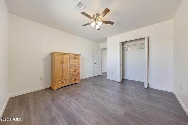 unfurnished bedroom featuring visible vents, baseboards, wood finished floors, a closet, and a ceiling fan