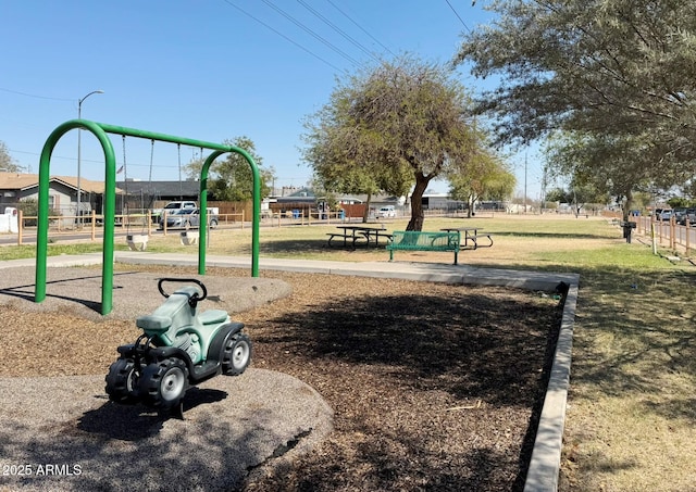 community play area featuring a lawn and fence