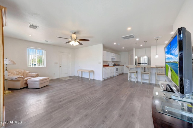 living area featuring visible vents, light wood-type flooring, and ceiling fan