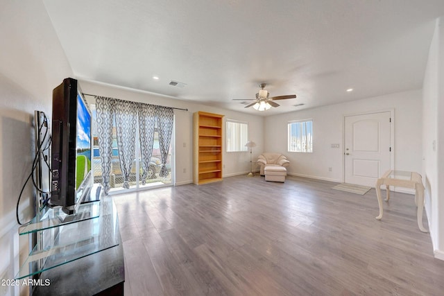 unfurnished living room featuring a ceiling fan, wood finished floors, visible vents, and baseboards