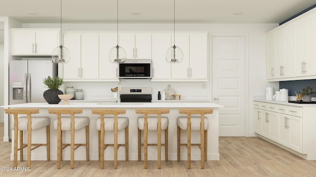 kitchen featuring white cabinets, range, hanging light fixtures, and a kitchen island with sink