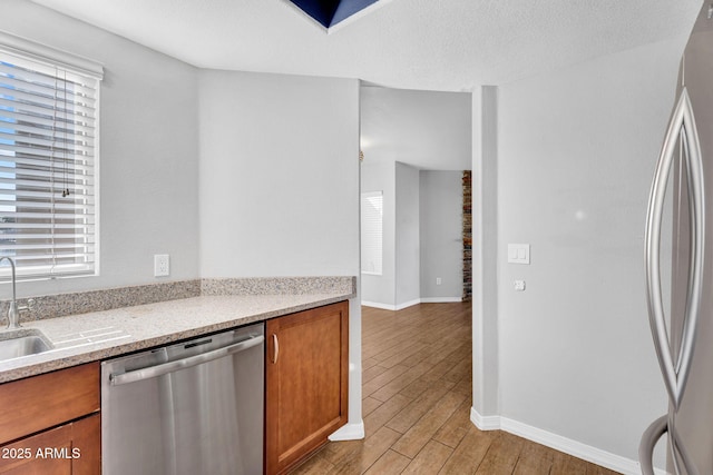 1825 W Ray Rd Unit 1119, Chandler, AZ 85224 - kitchen with stainless steel appliances, brown cabinets, light wood-style flooring, a sink, and baseboards
