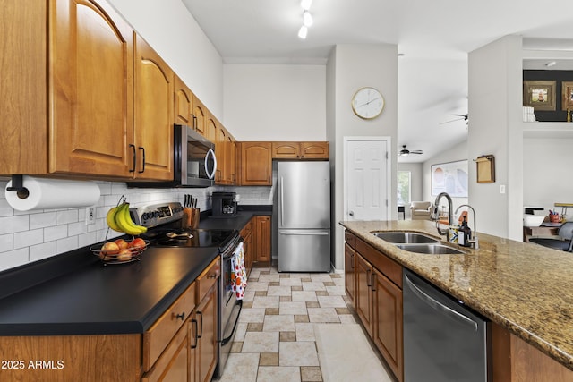15969 W Adams St, Goodyear, AZ 85338 - kitchen with stainless steel appliances, backsplash, brown cabinetry, dark stone countertops, and ceiling fan