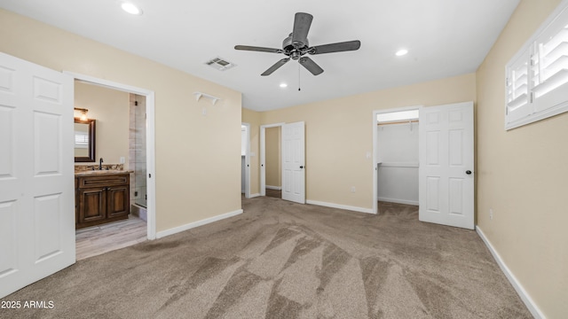 unfurnished bedroom with a sink, baseboards, a spacious closet, visible vents, and light colored carpet